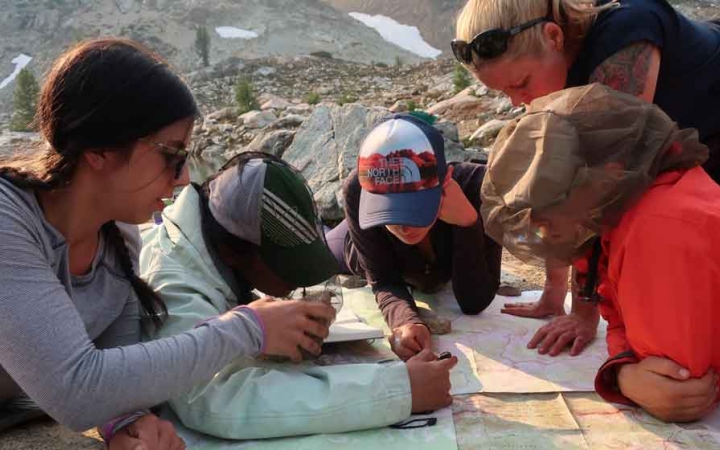 a group of gap year students examine a map while mountaineering with outward bound